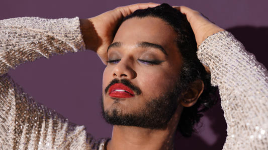 photo of a person with a beard, red lipstick, and purple eyeshadow looking euphoric